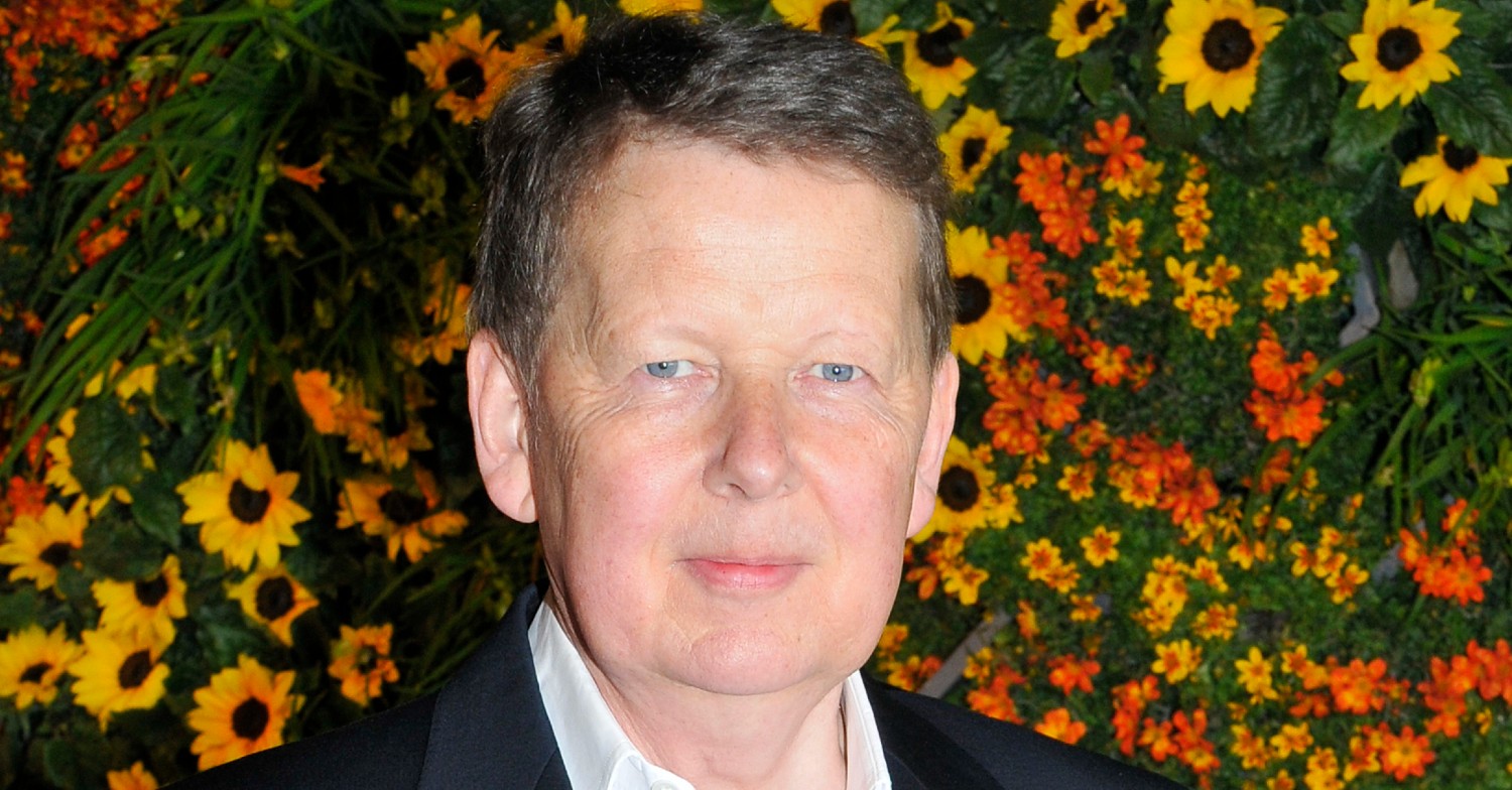 BBC star Bill Turnbull next to a wall of yellow and orange flowers
