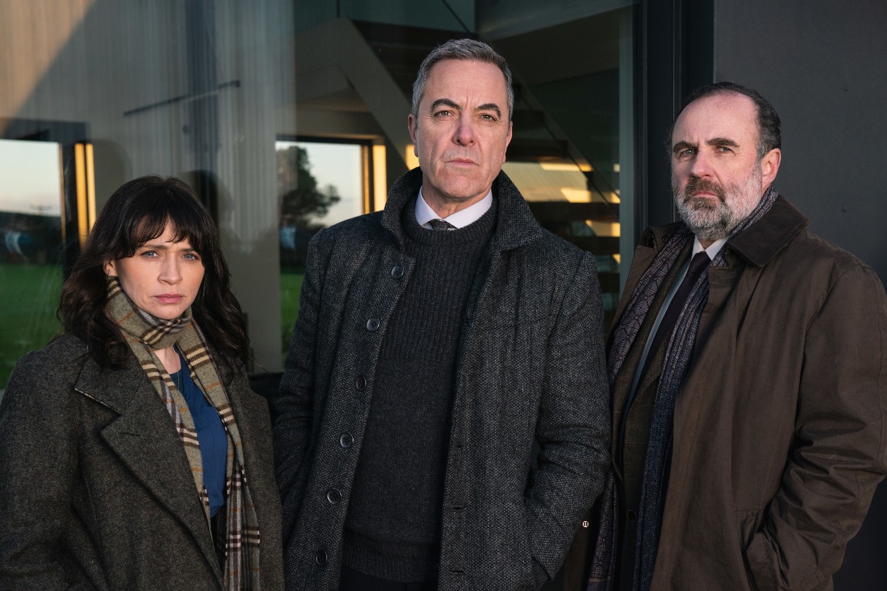 Charlene McKenna as Niamh (left), James Nesbitt as Tom (middle) and Lorcan Cranitch as Jackie in Bloodlands, they stand together outside a house with worried facial expresiions
