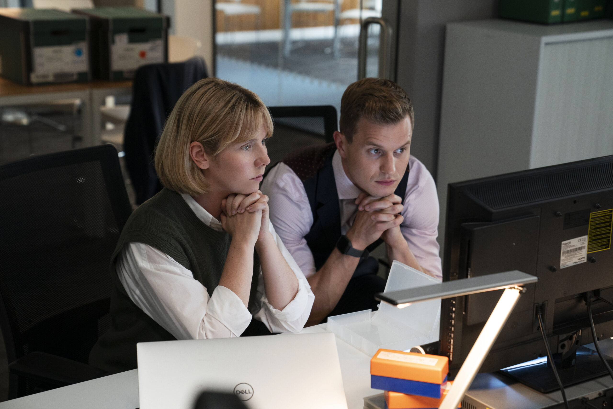 CHRIS JENKS as DS Murray (right) and LAUREN LYLES as Karen (left), they look at a computer with worried expressions