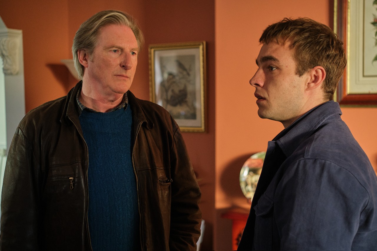 Adrain Dunbar as Ridley (left) and Nico Mirallegro as Cal (right) they stand in Cal's flat and both look angry