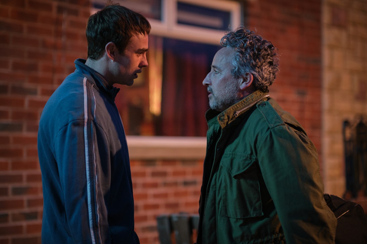 Nico Mirallegro as Cal (left) and Aidan McArdle as Michael Flannery, the pair stand together outside his house in a flashback