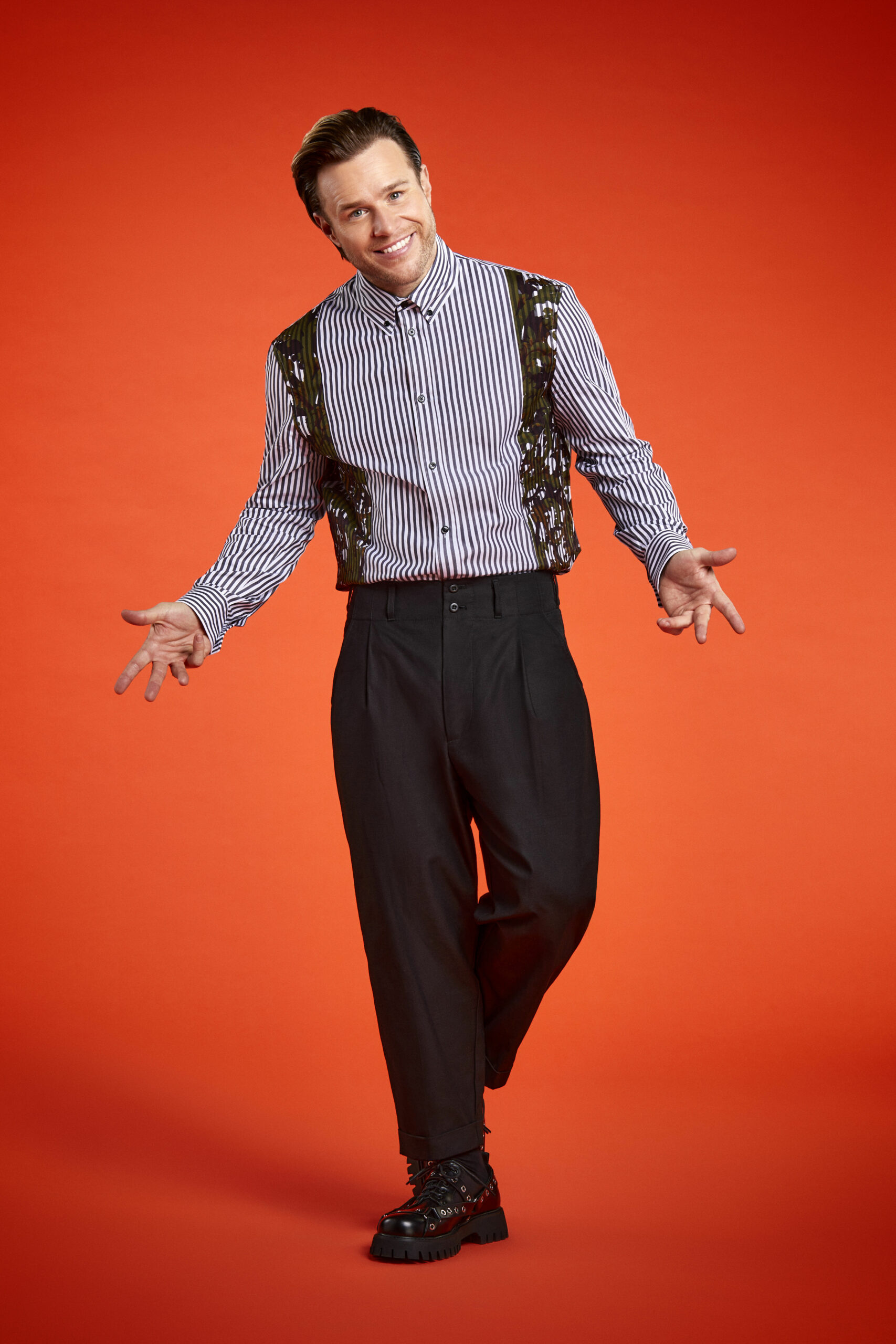 Olly Murs standing against a bright orange background
