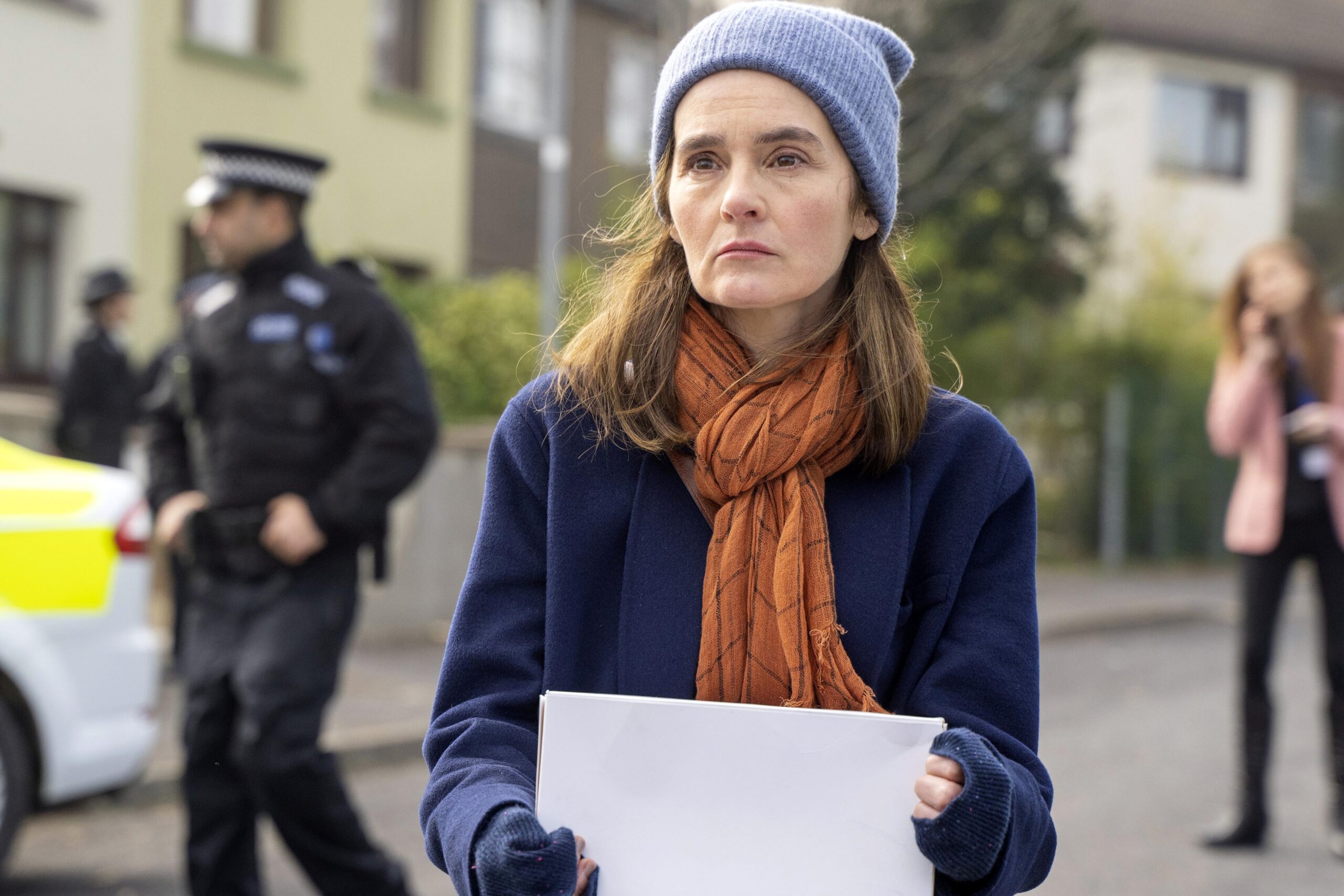 Shirley Henderson as Claudia in The House Across The Street, she holds a poster with a worried face outside near police