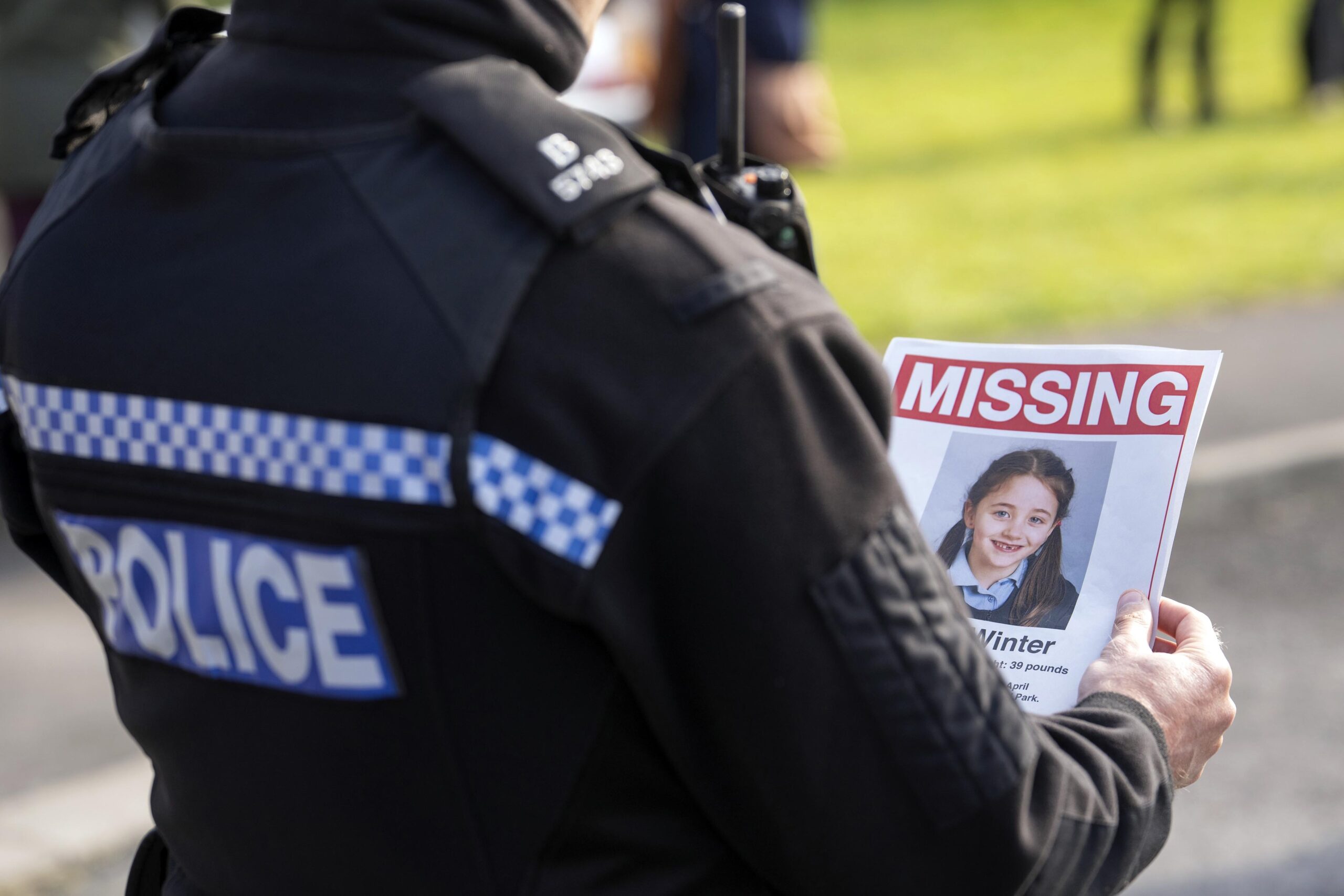 A police officer holds up a missing poster with Emily Winters on it 
