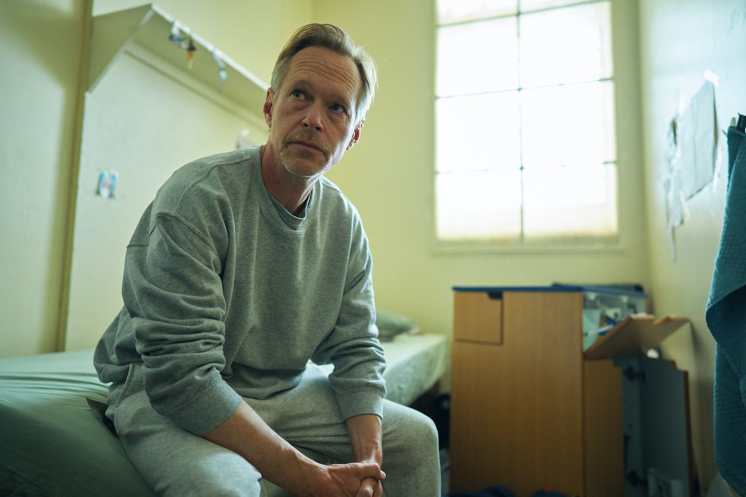 The Pact's Harry in his prison wearing a pale tracksuit 