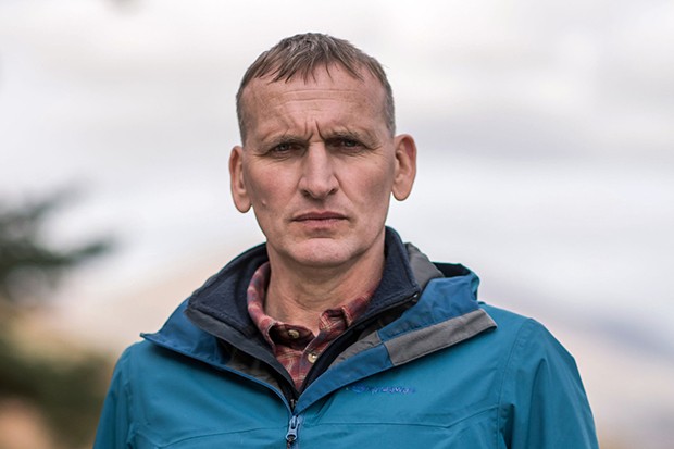 Christopher Ecclestone as Maurice in The A Word, he is outside and looks into the camera with a small smile and a blue coat on