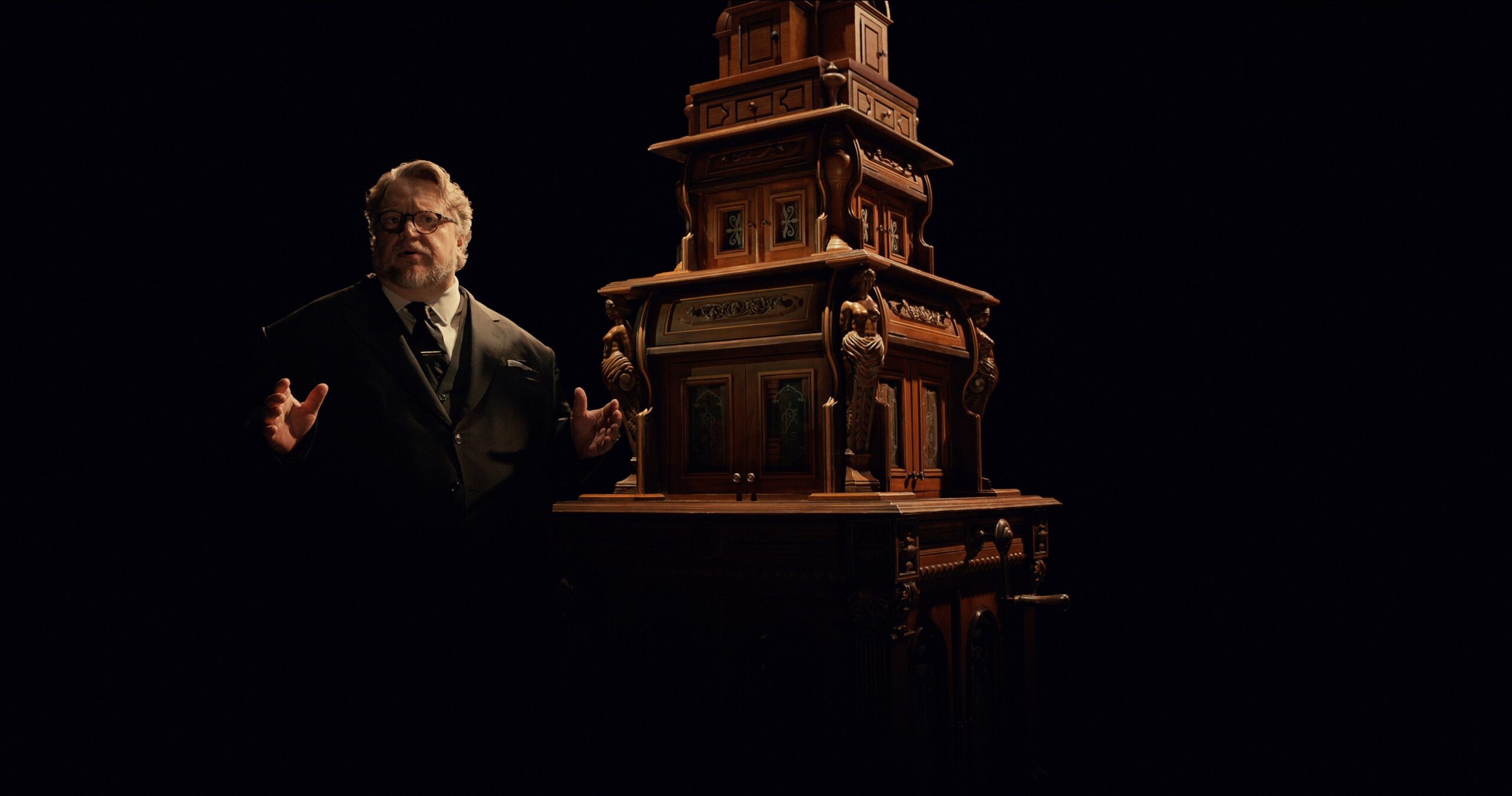 Guillermo del Toro stands in front of a real cabinet of curiosities