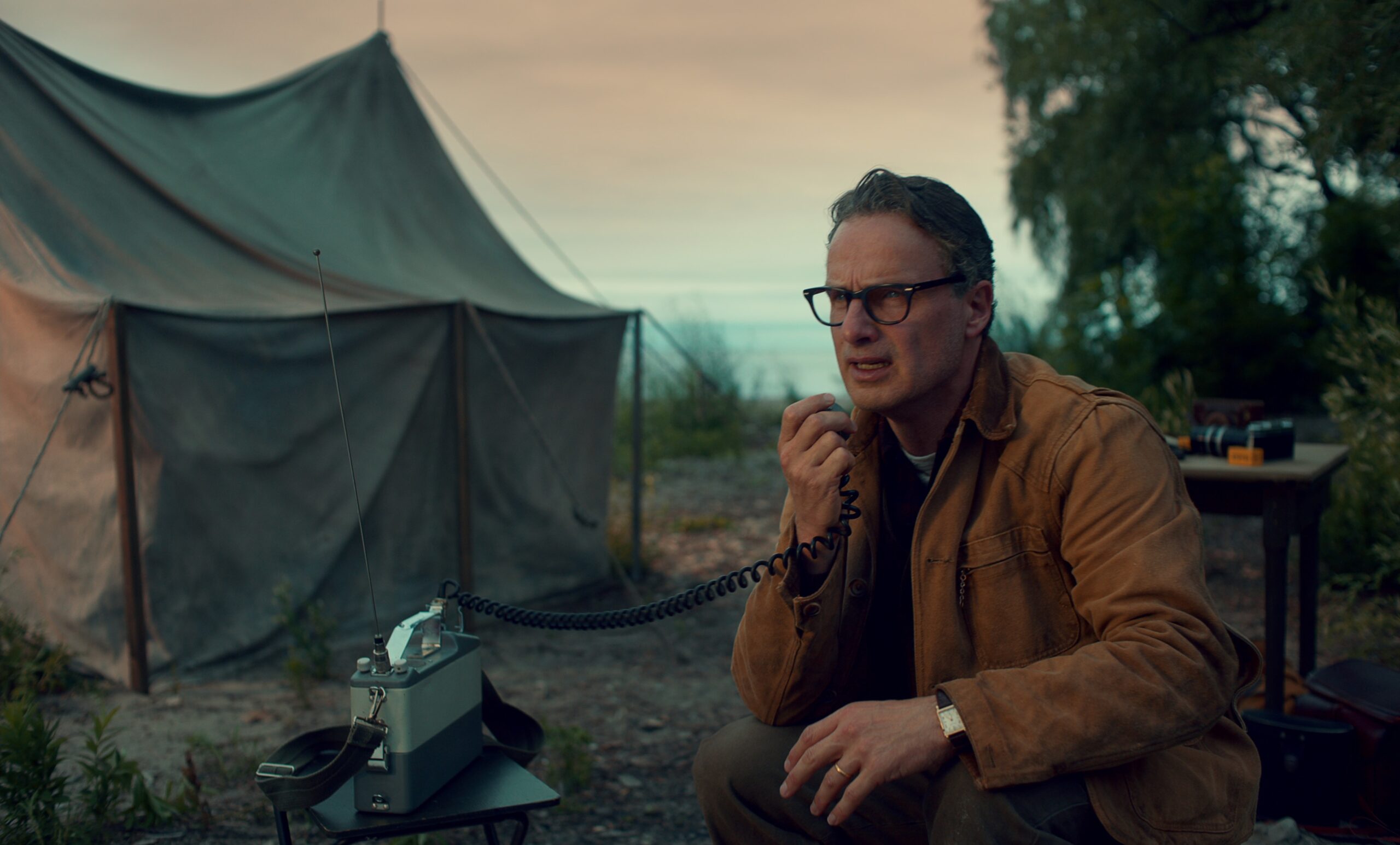 Andrew Lincoln is on an old fashioned radio by a mess tent