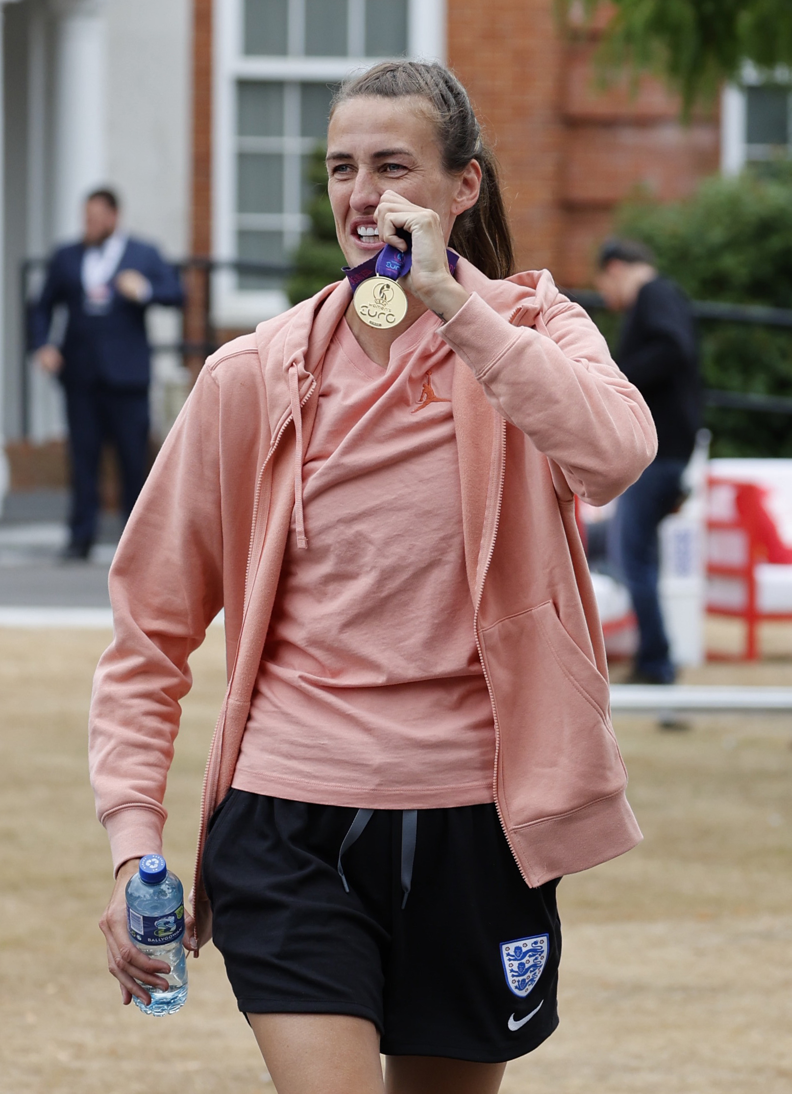 Jill Scott wearing a peach top and hoodie holding a medal