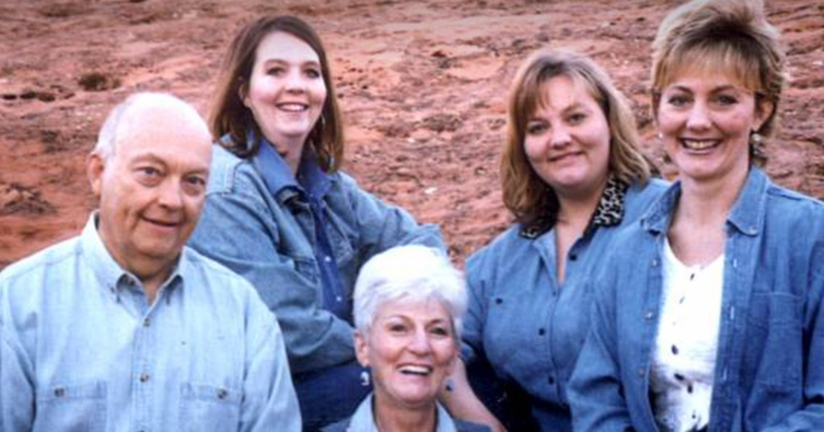 Image of the Broberg family including Jan Broberg, they all smile next to a mountain range in blue shirts