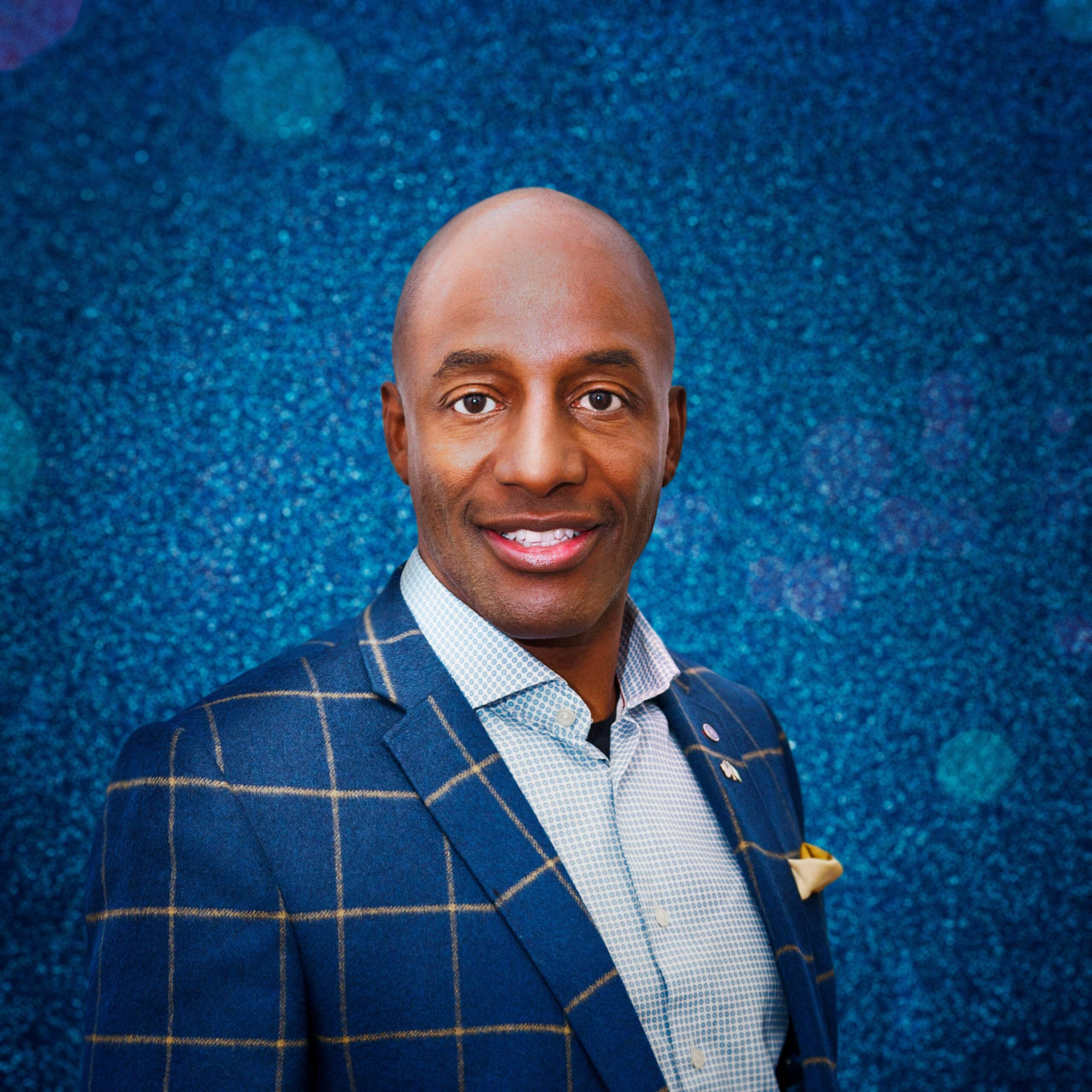 John Fashanu standing in front of blue glitter boarding for Dancing On Ice