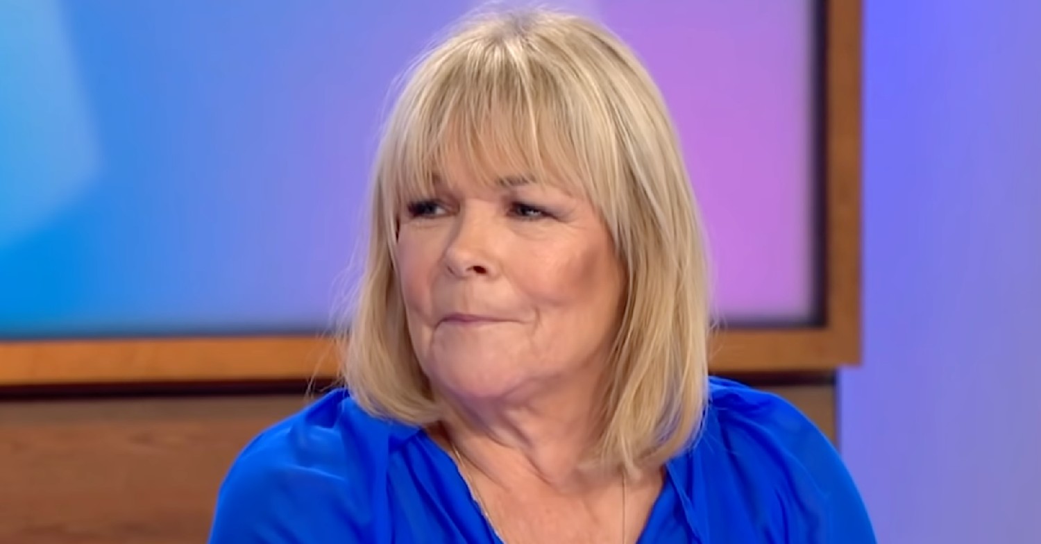 Linda Robson smirking in blue top on Loose Women