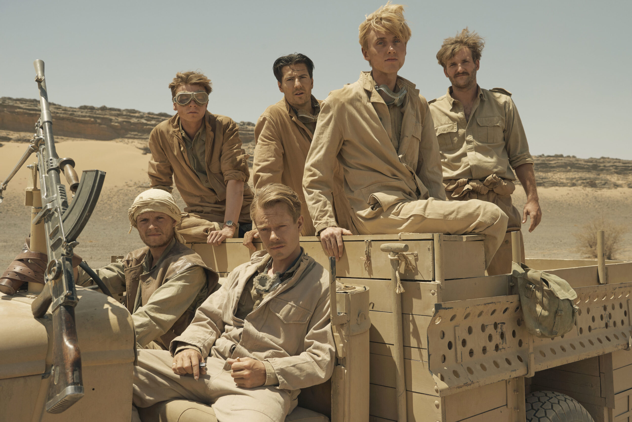 The cast of SAS Rogue Heroes sitting in a Jeep