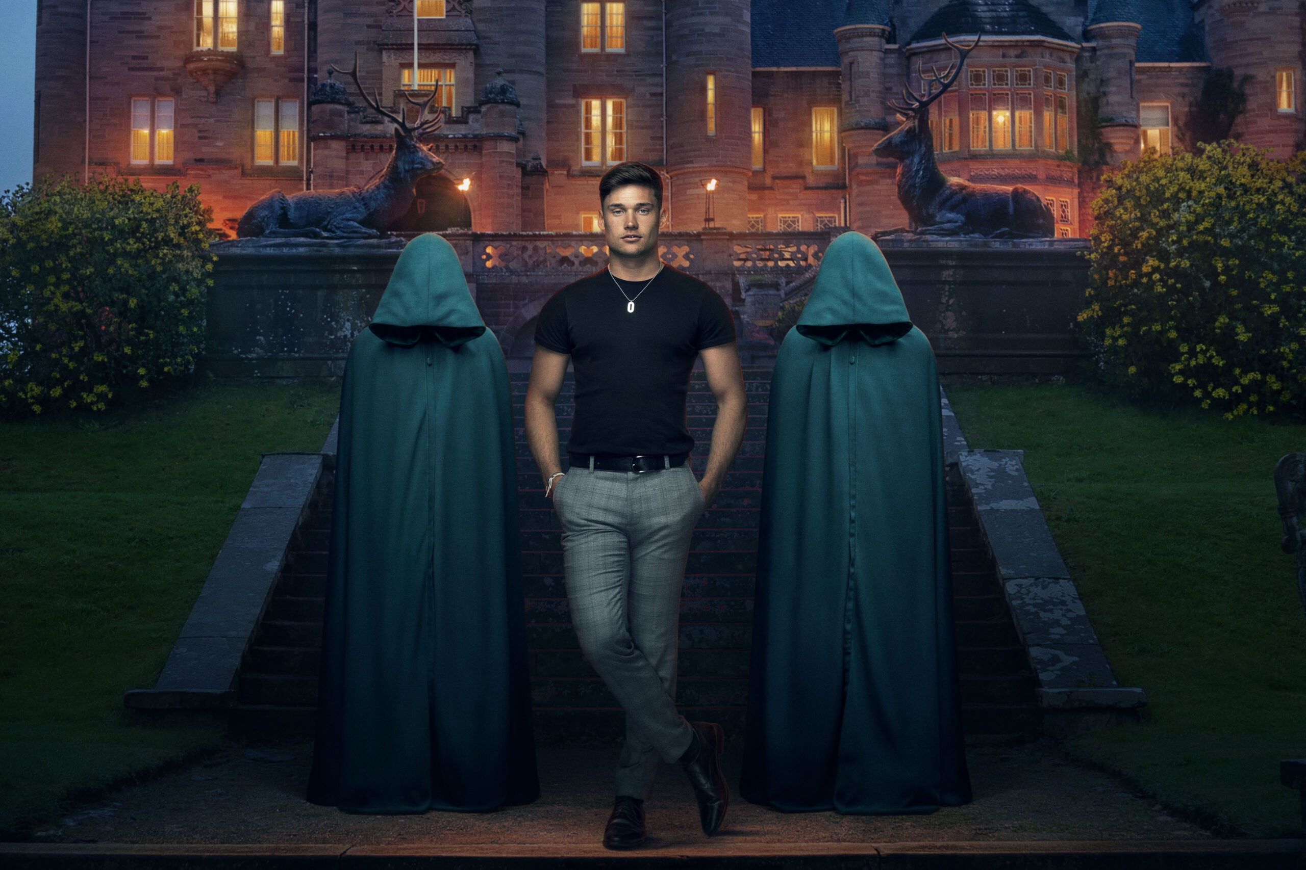 Aaron smiles for The Traitors with two robes behind