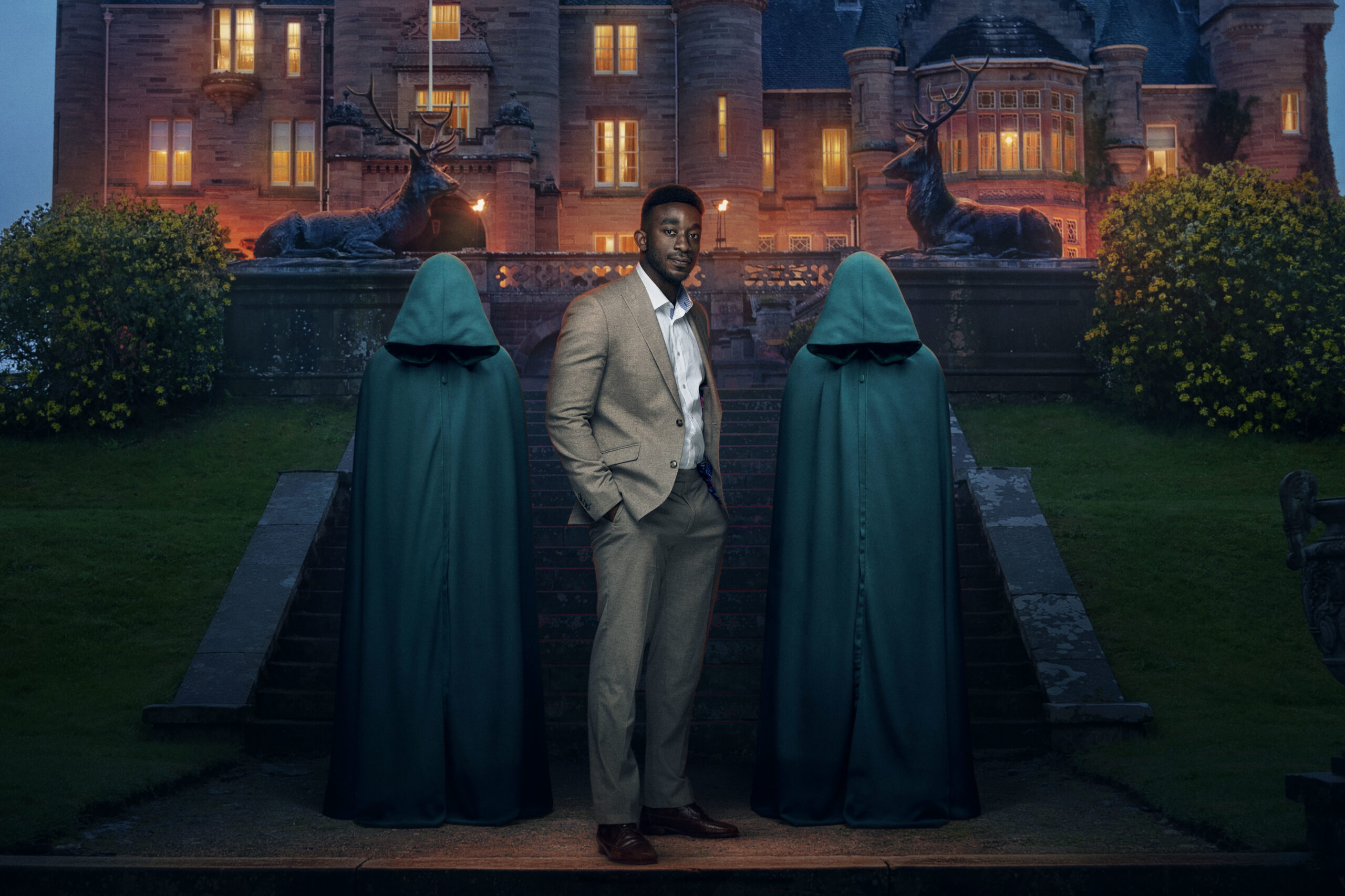 Amos smiles between the two hoods in The Traitors