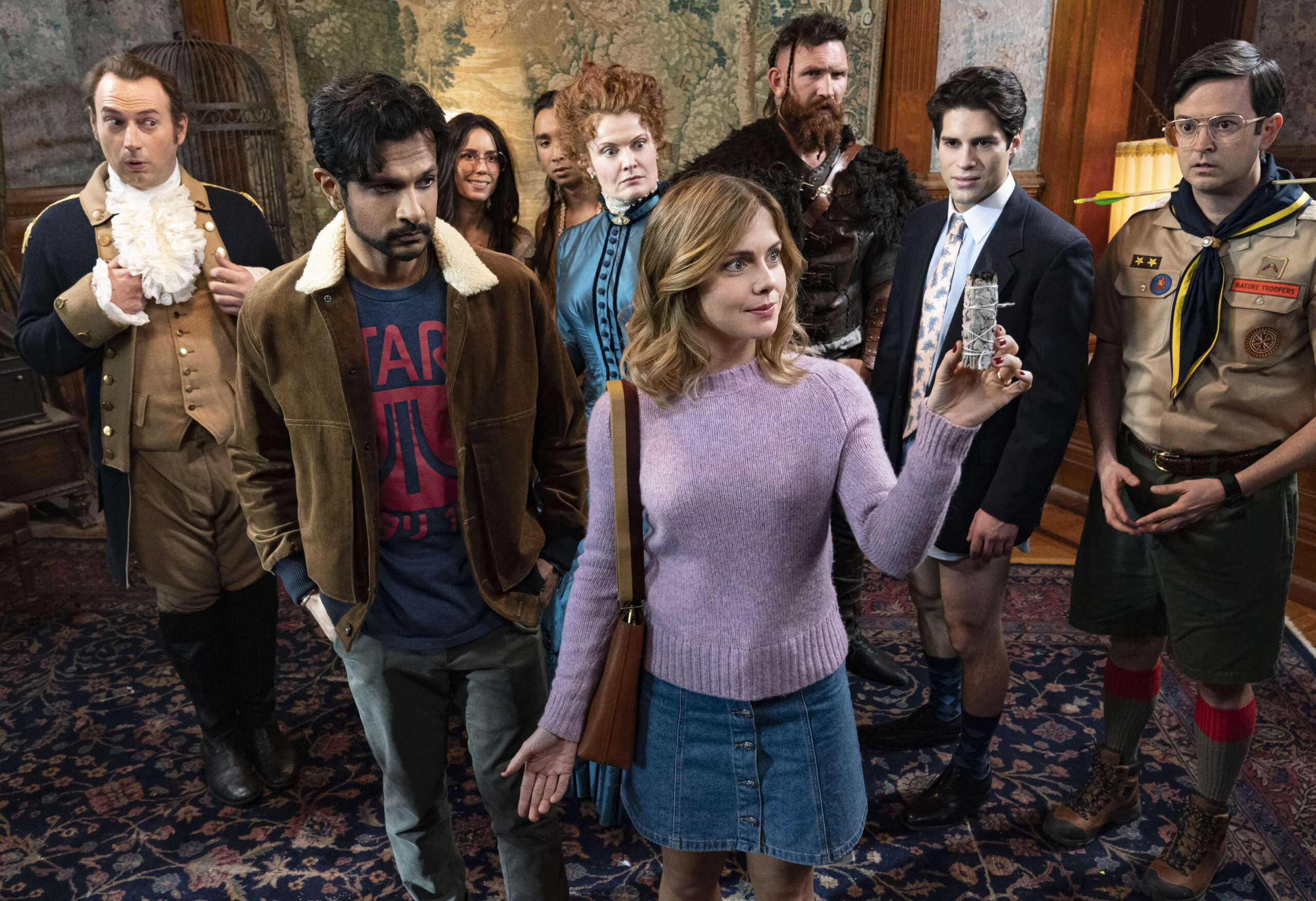 Sam holds up an item with Jay and the Ghosts behind her
