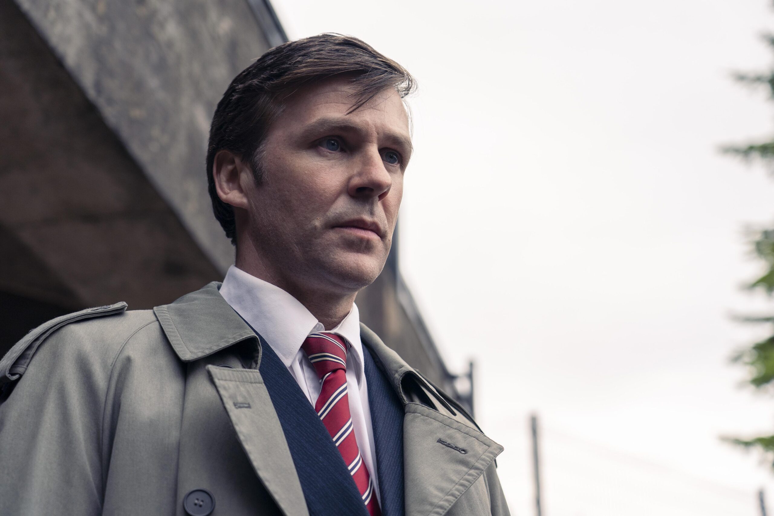 Paul Berowne stands outside in a suit in Dalgliesh