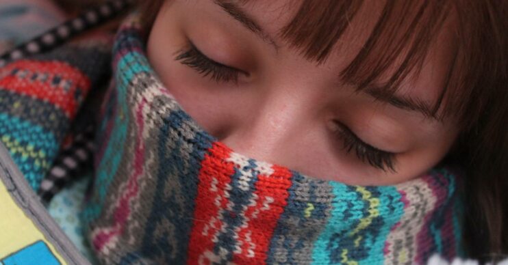 A woman sleeps with a scarf on her face