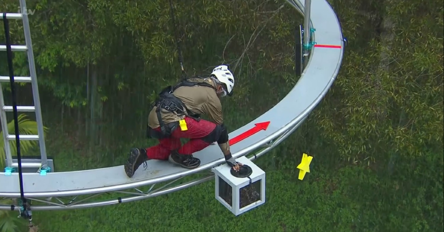 Babatunde squatting down on the platform on I'm A Celebrity 