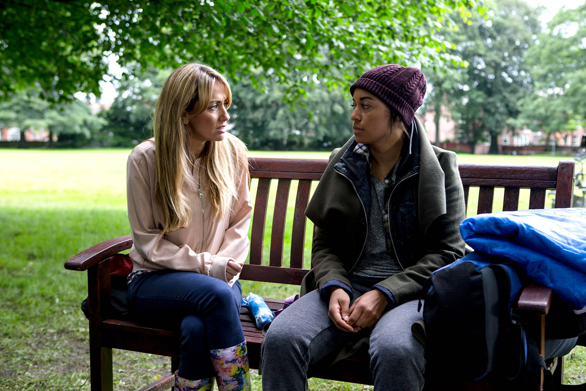 Maria looking worried at Caz as they sit on a park bench in Corrie 
