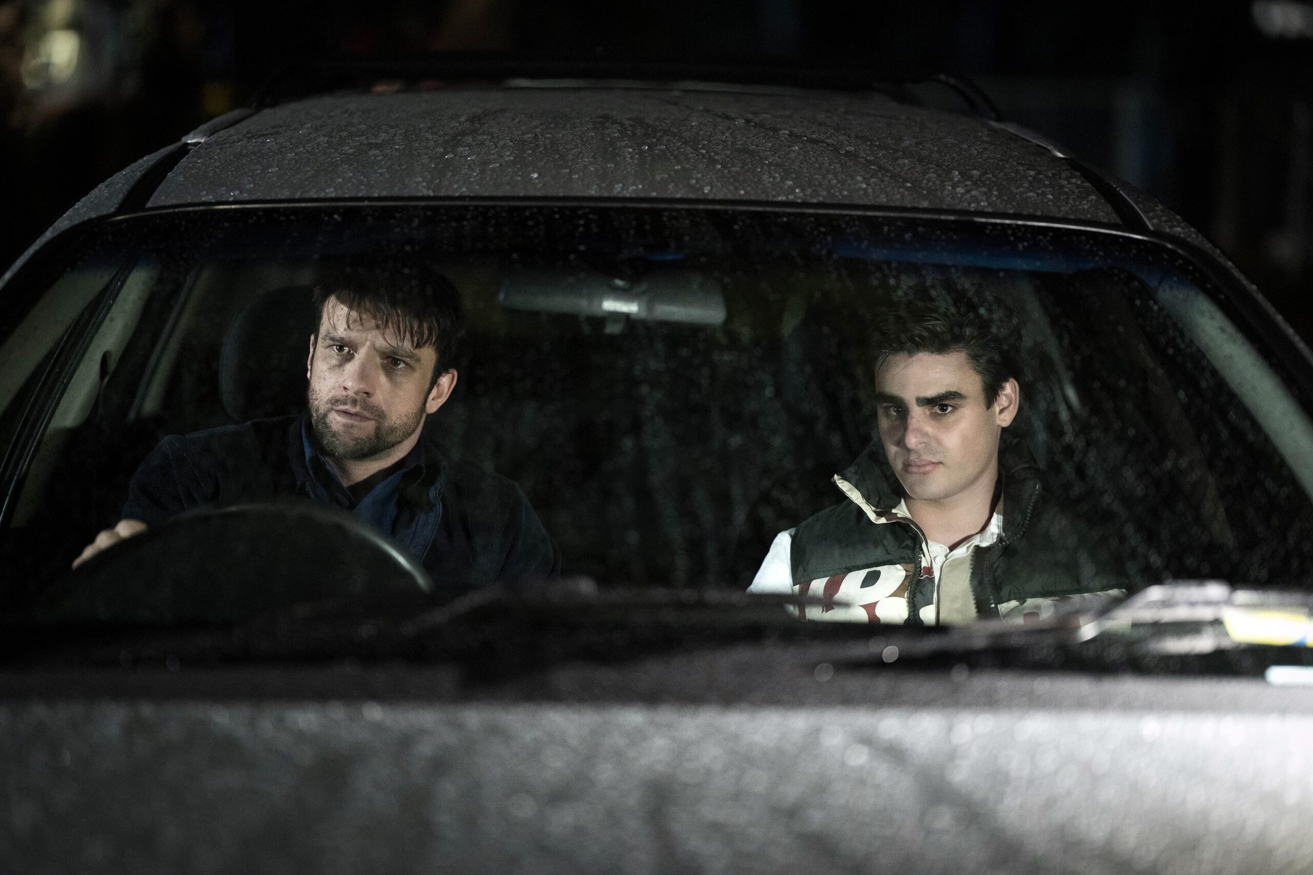 Michael and Logan frown in a car in Riptide