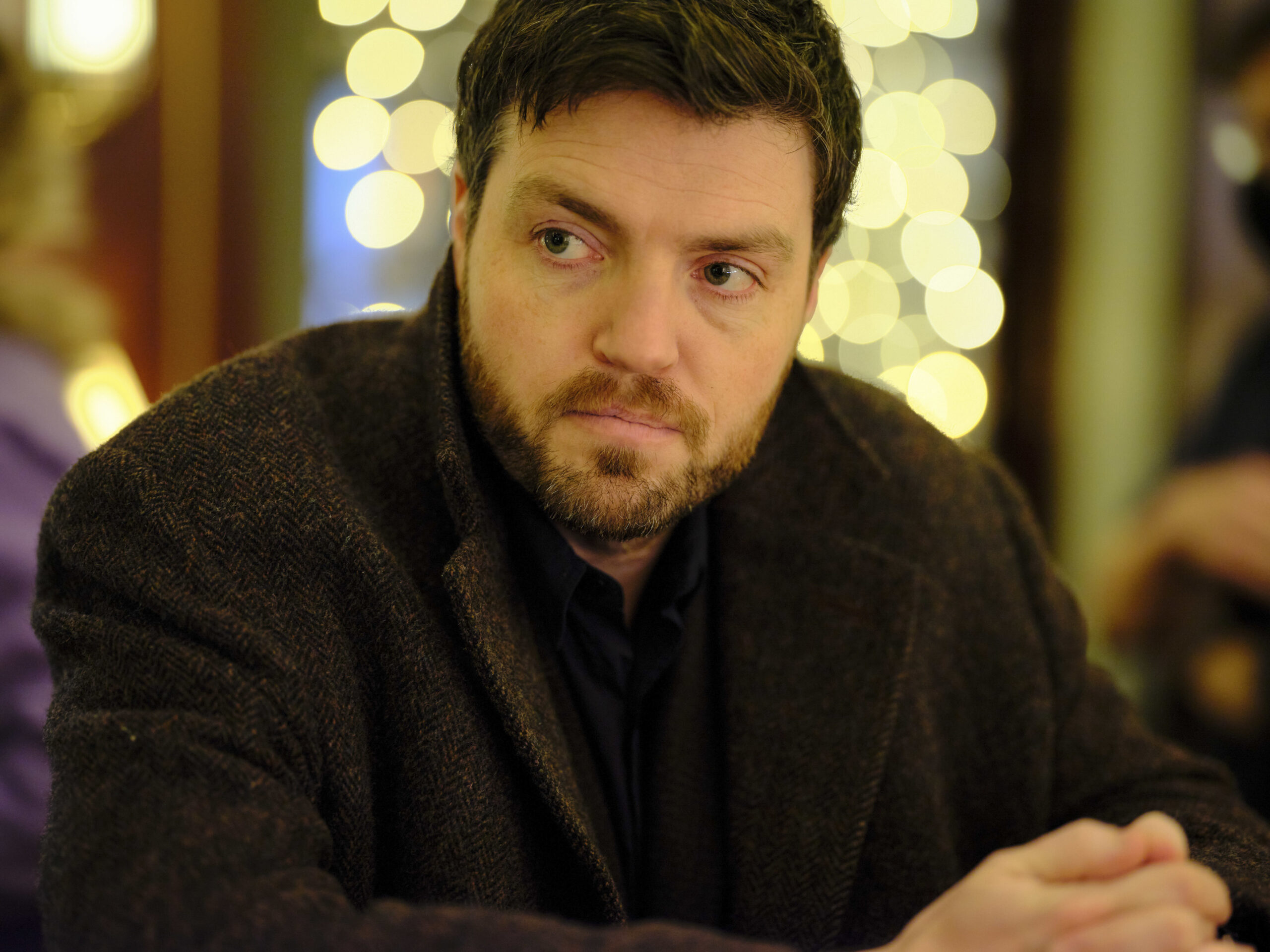 Cormoran Strike looks to his left in a bar 