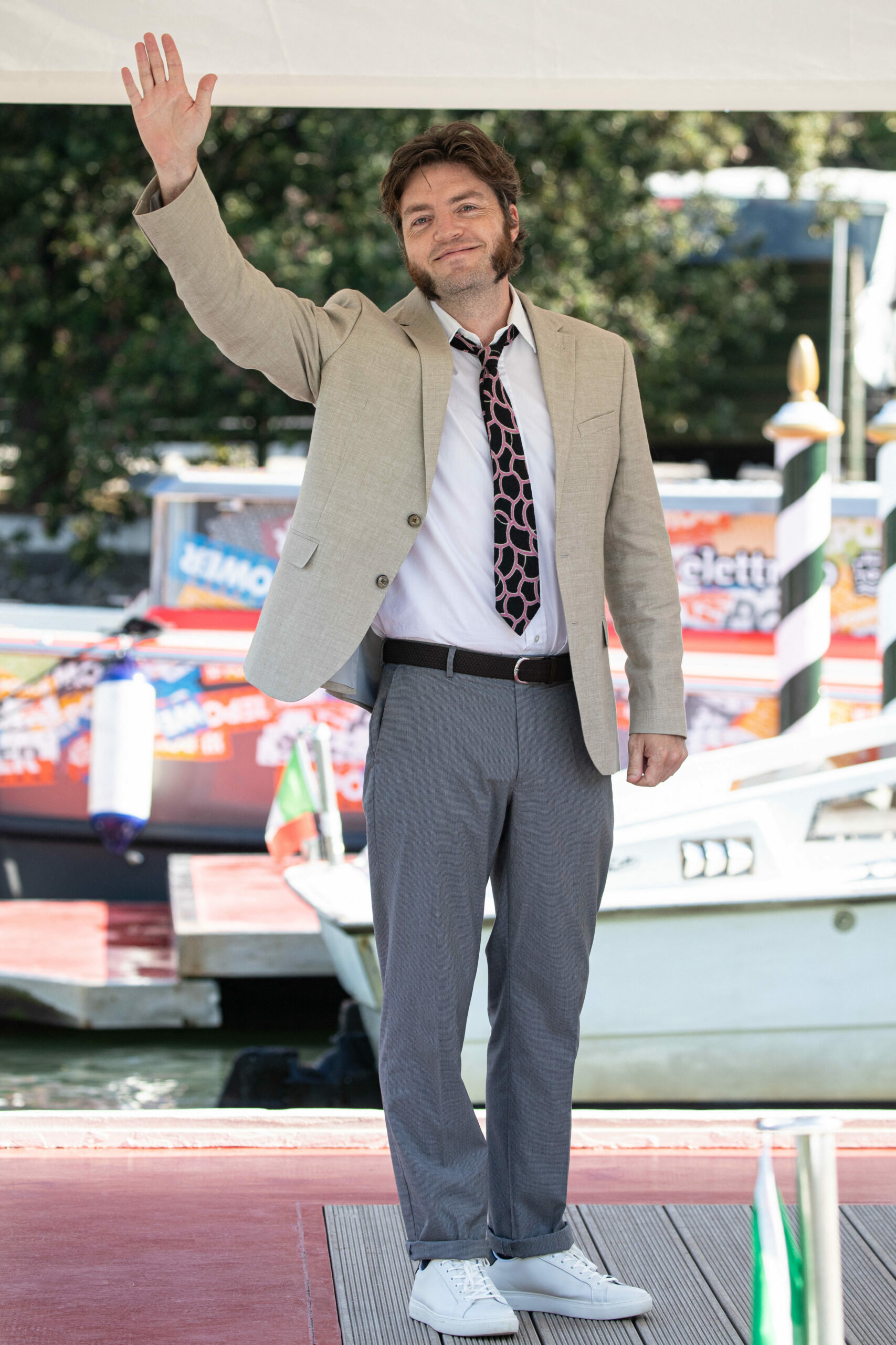 Tom Burke waves at the 2021 Venice Film Festival