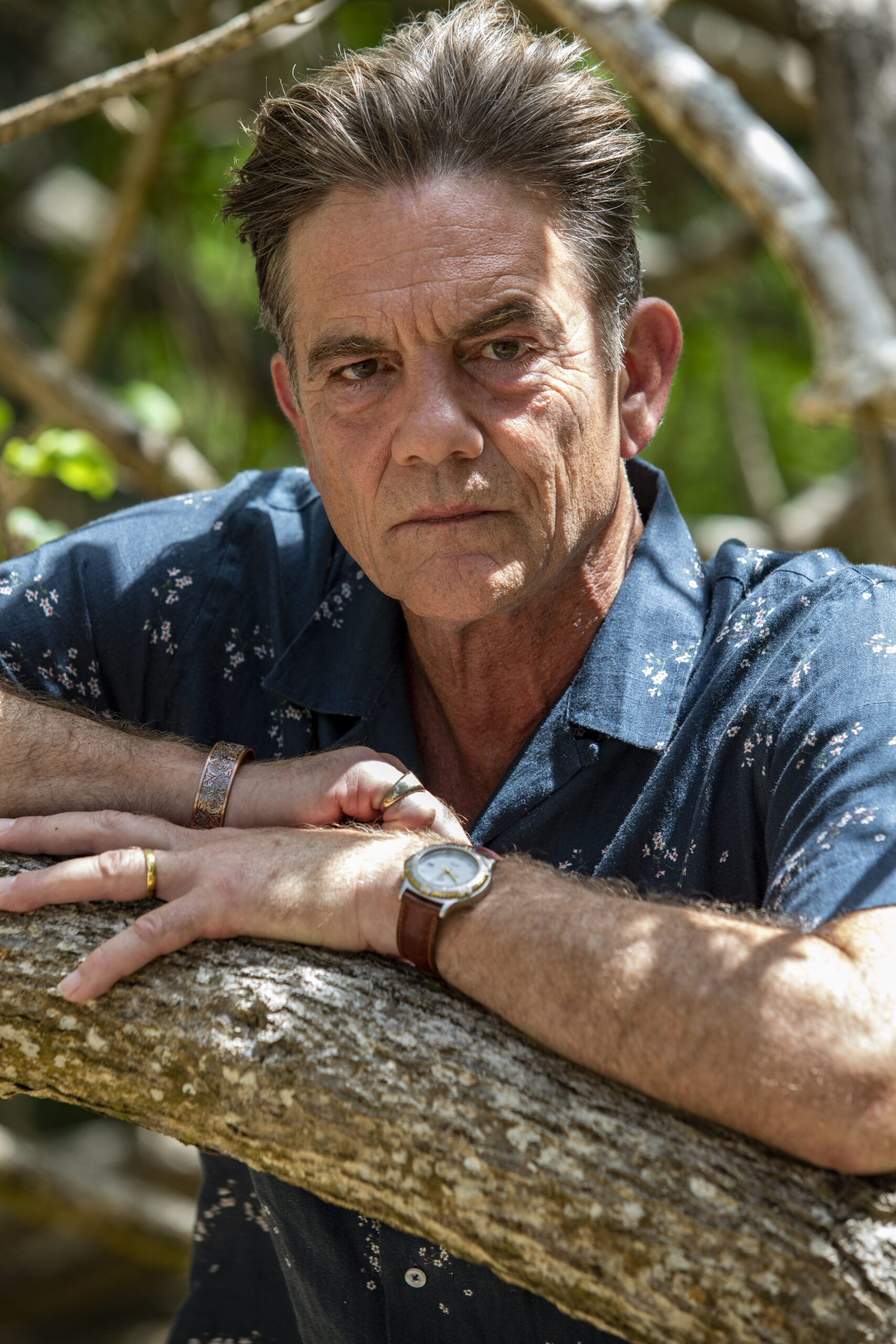 John Michie posing next to a tree in Death in Paradise 