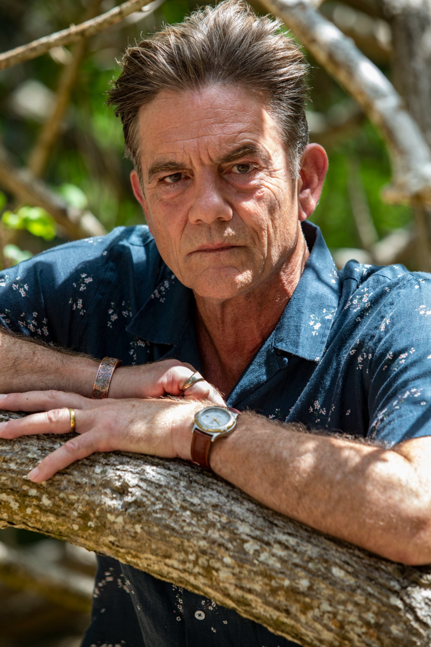John Michie posing next to a tree in Death in Paradise