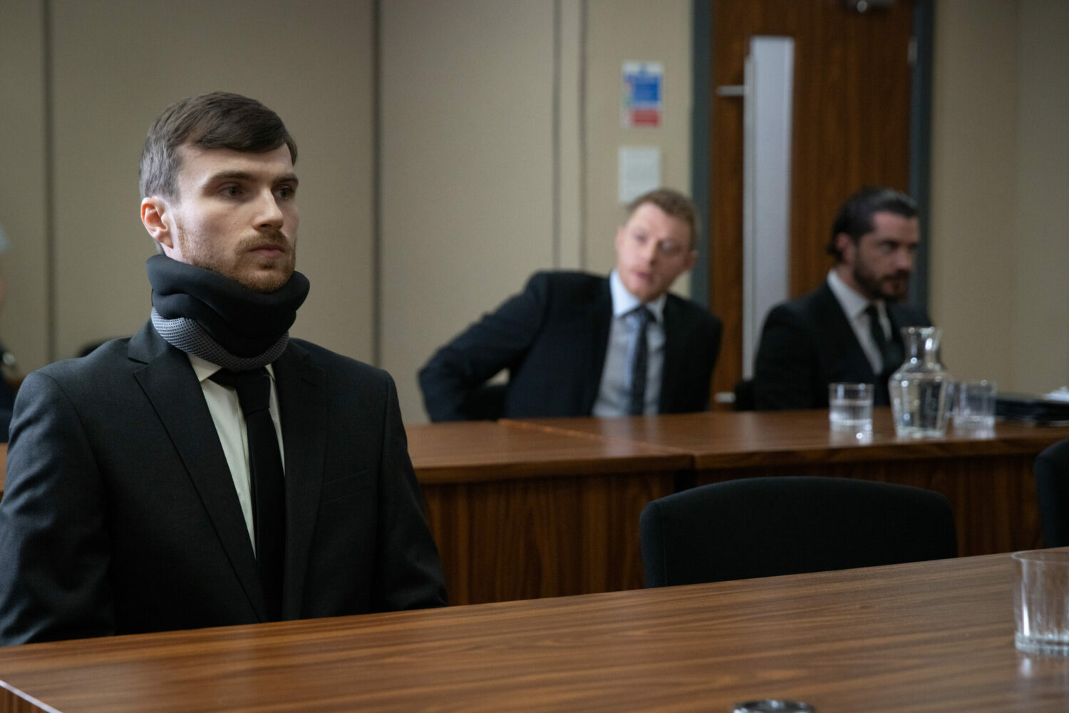 Justin in Coronation Street wears a neckbrace to court and stares straight ahead