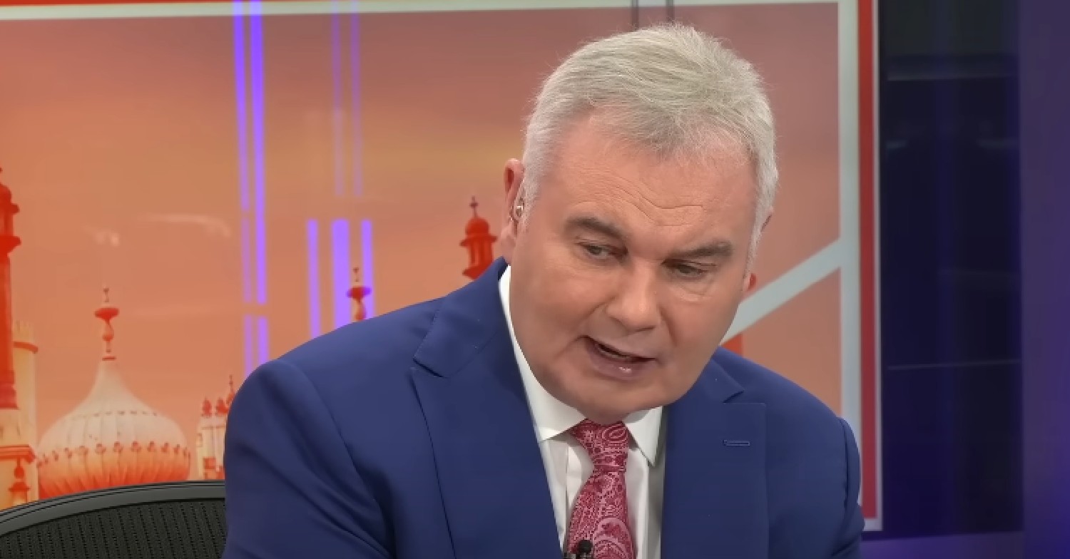 Eamonn Holmes in blue suit looking down on GB News