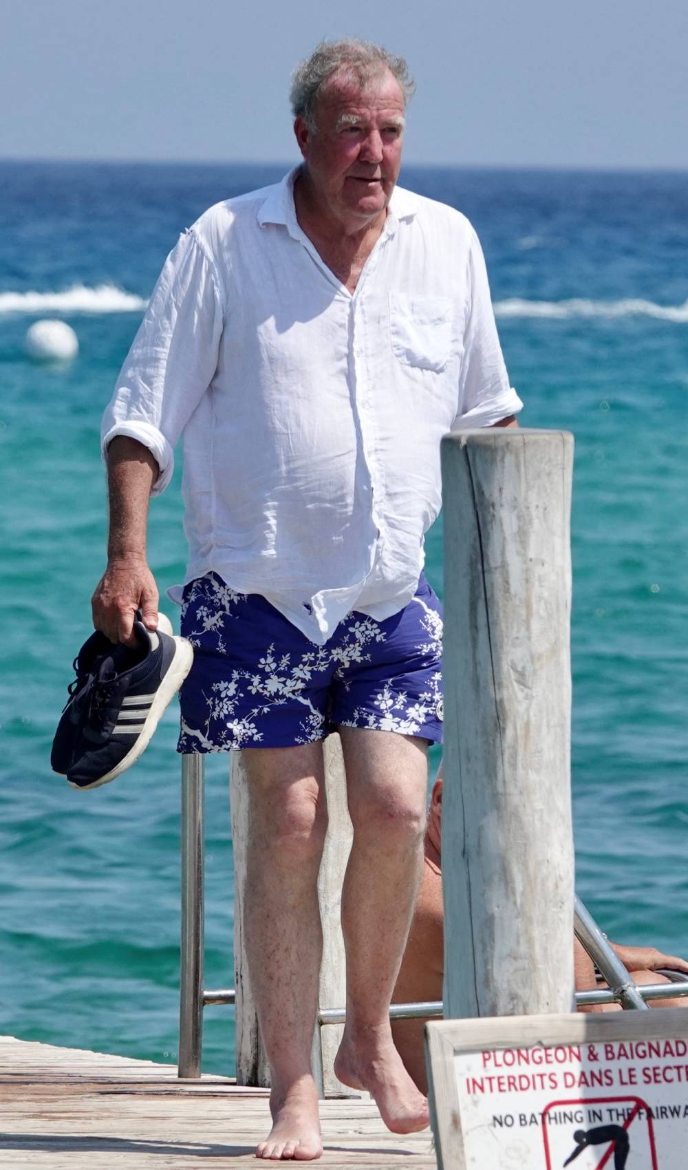Jeremy Clarkson walks with trainers in his hand