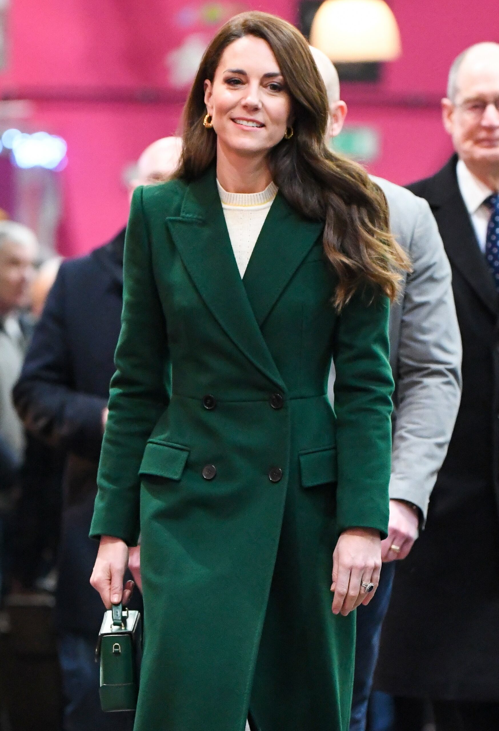 Kate, Princess of Wales, smiling in green coat during royal engagement