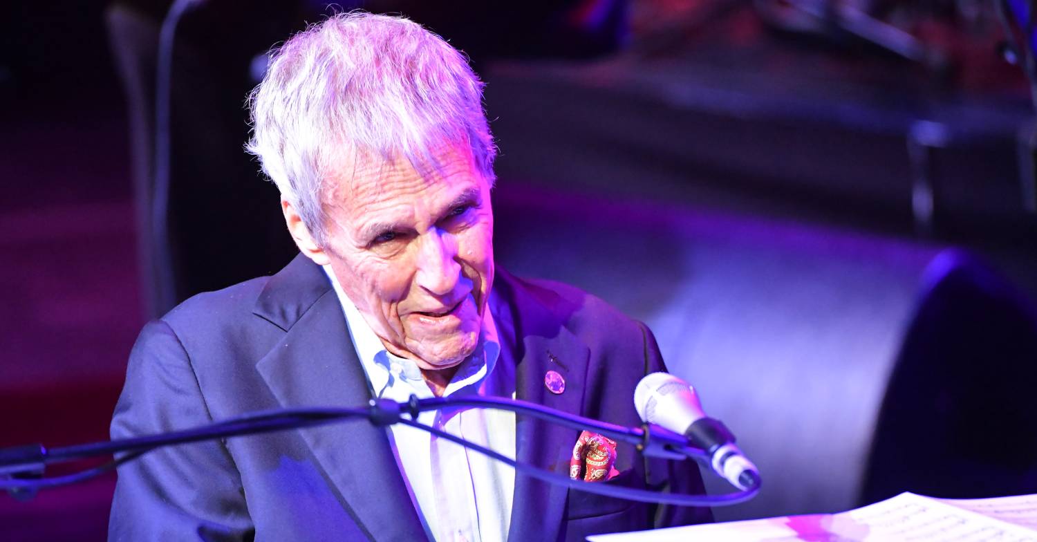 Burt Bacharach smiling at piano with microphone