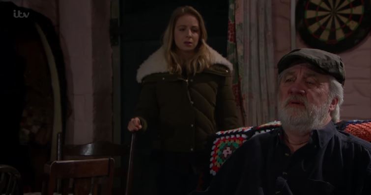 Zak looks upset and pained while Belle stands in the background worried (Emmerdale)