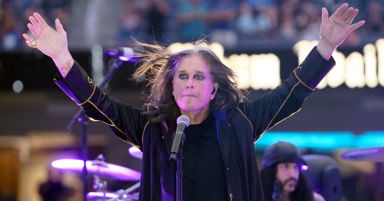 Ozzy Osbourne with his arms in the air on stage