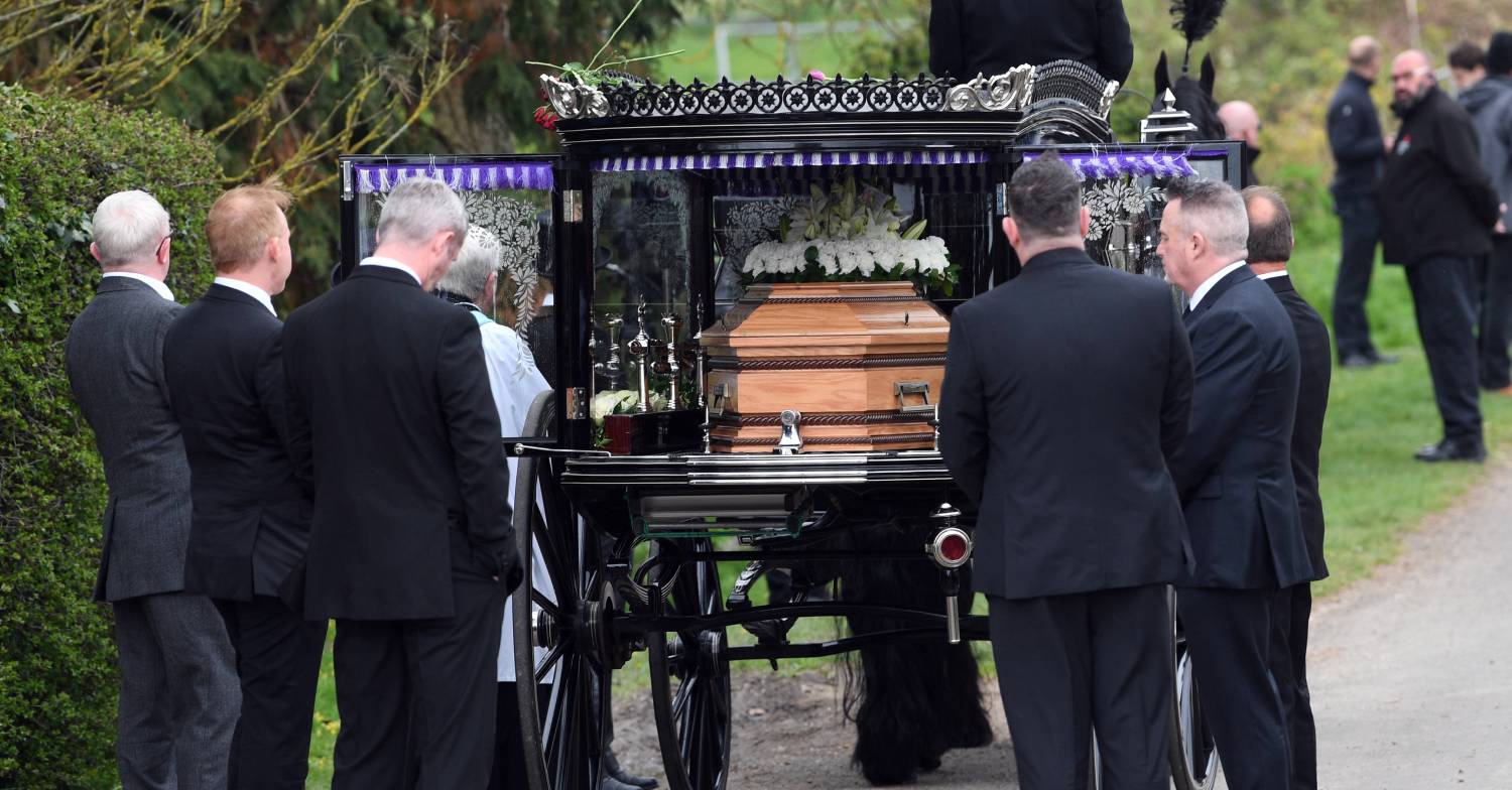 Pallbearers stand by the hearse