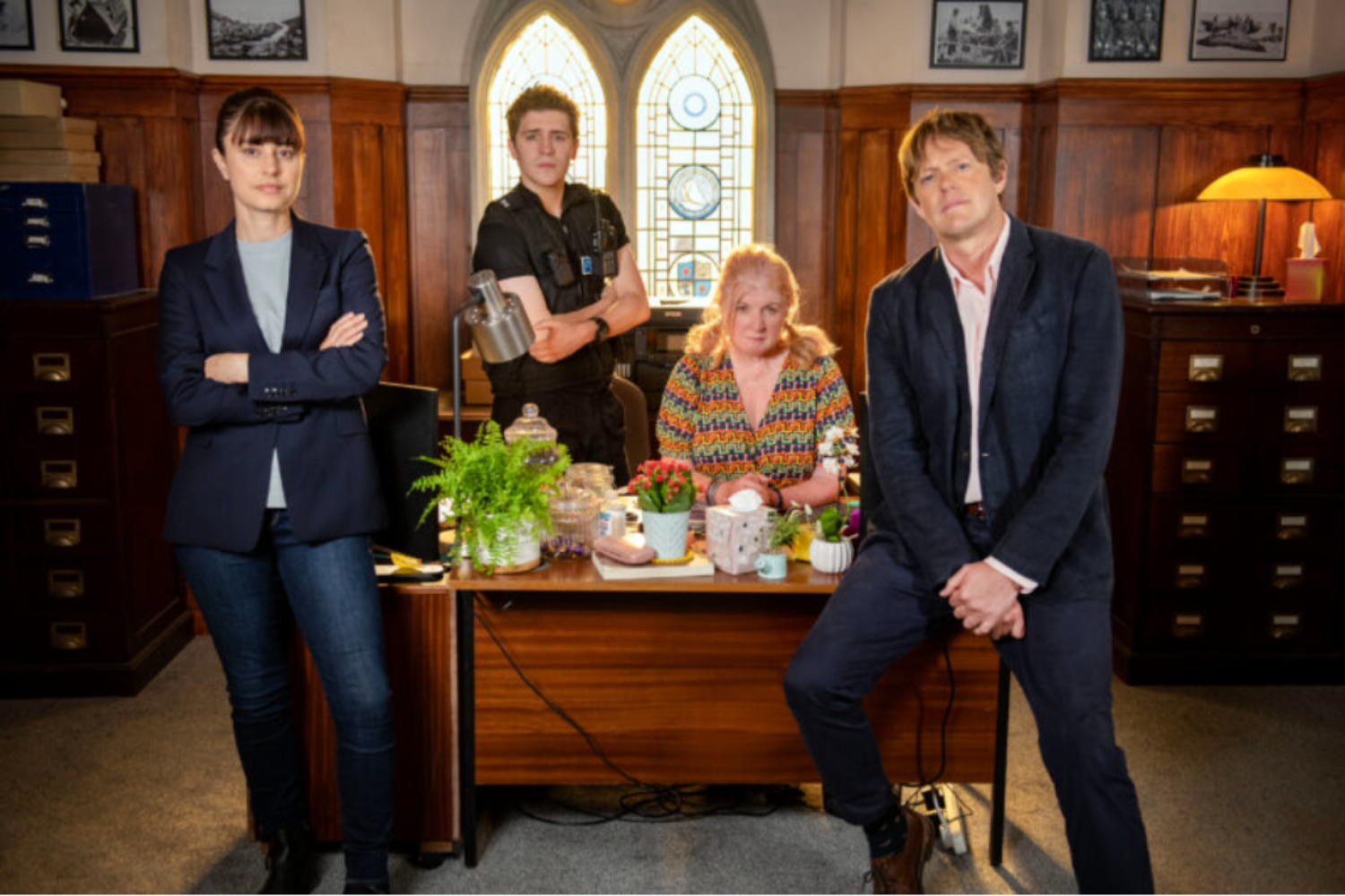 The cast of Beyond Paradise sitting in an office