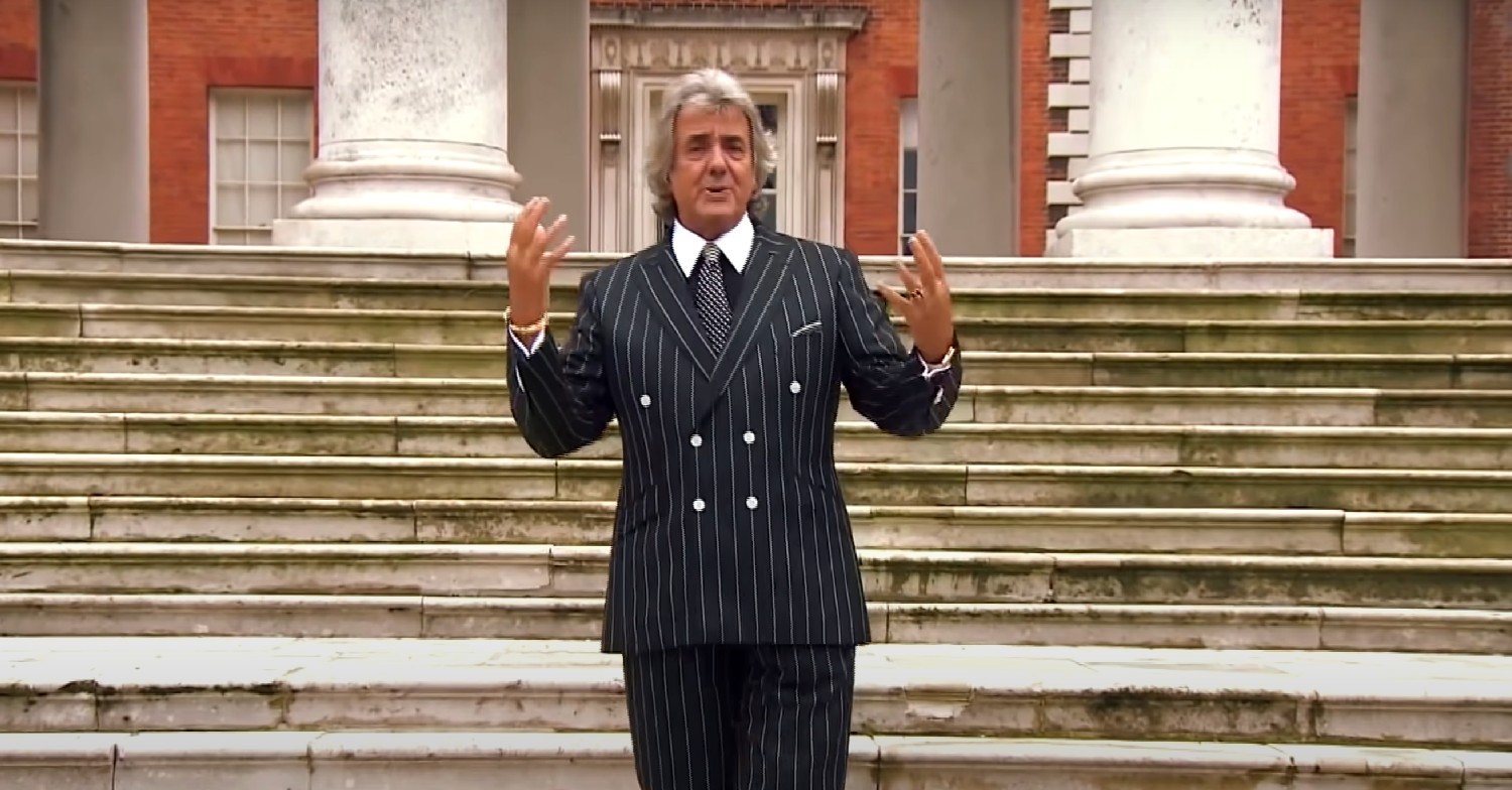 David Dickinson walking down some steps, speaking to camera 