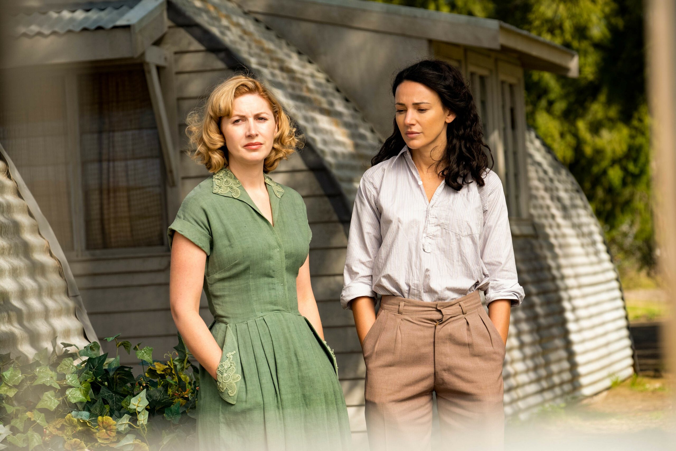 Sheila and Kate stand with their hands in their pockets in Ten Pound Poms