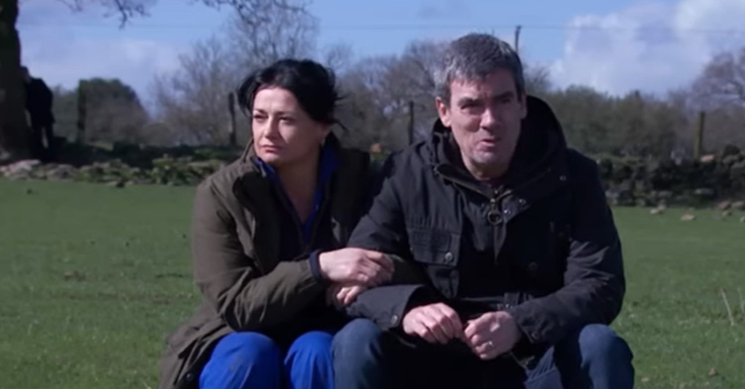 Emmerdale's Cain and Moira are sitting in the field with Caleb watching in the distance