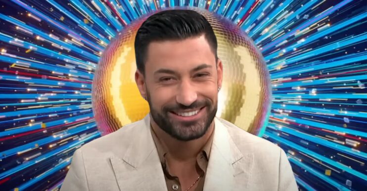 Giovanni Pernice smiling in front of Strictly logo