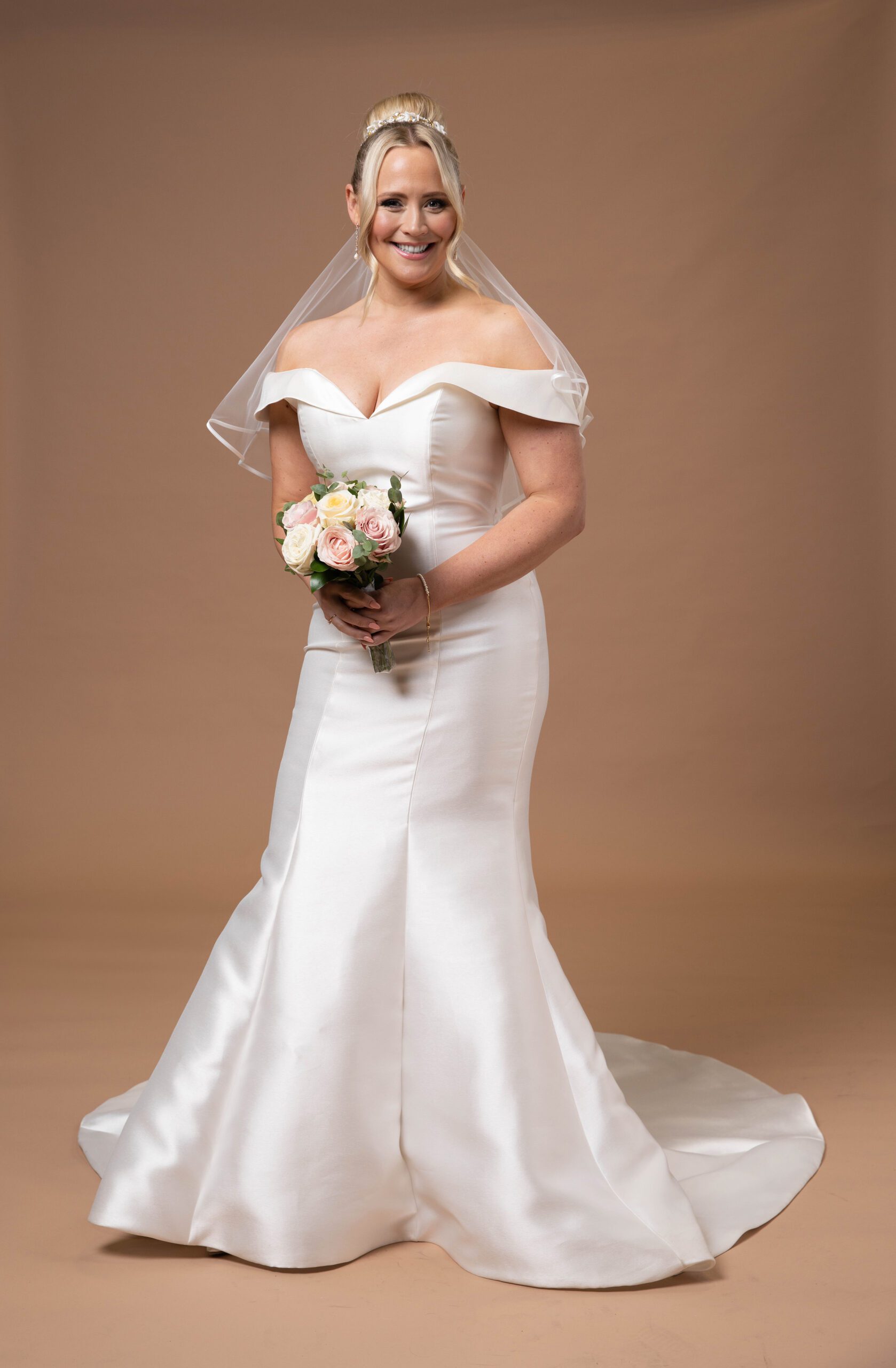Emmerdale's Tracy is in a wedding dress and veil, holding a bouquet of flowers