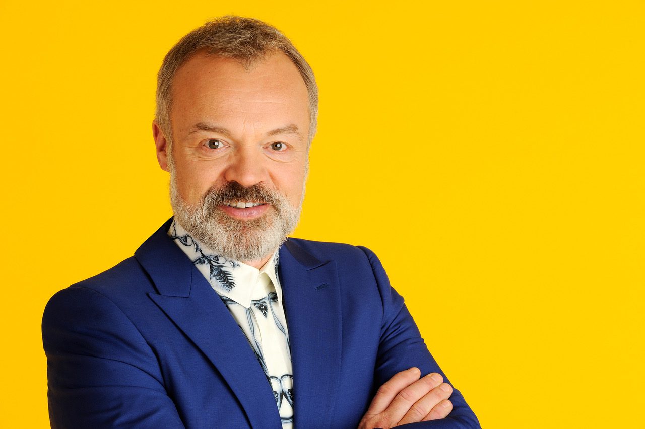 Graham Norton poses in front of yellow background