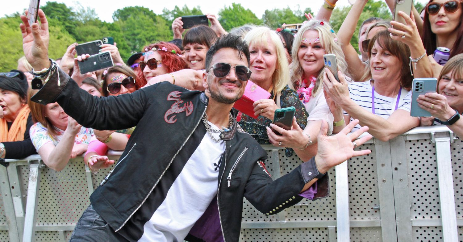 Peter Andre standing smiling with fans at a music event