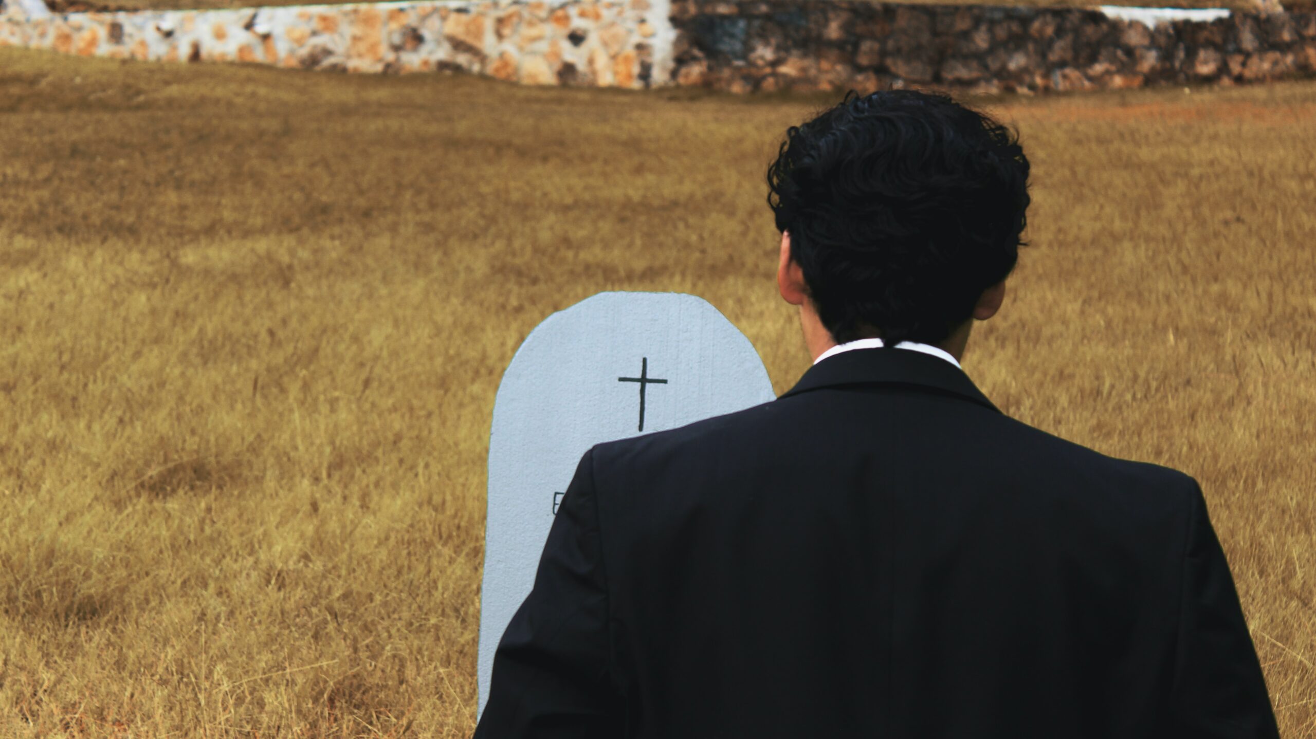 Man looks at coffin in a graveyard