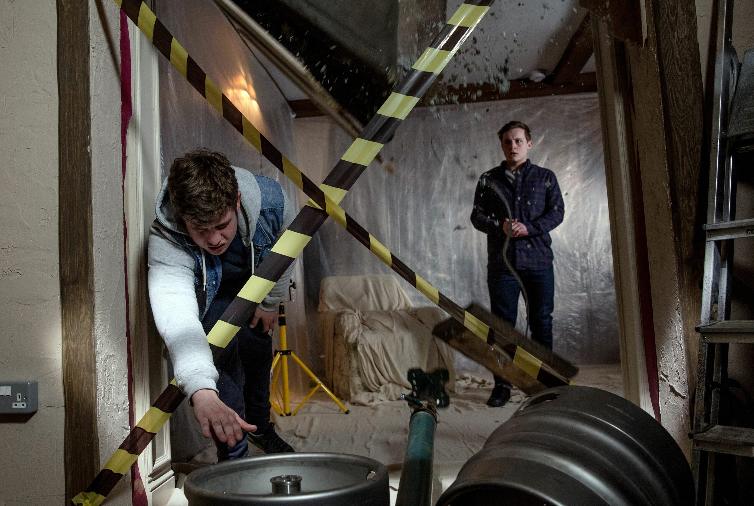 Gerry leans over in Emmerdale and moves a barrel as Lachlan White looks on
