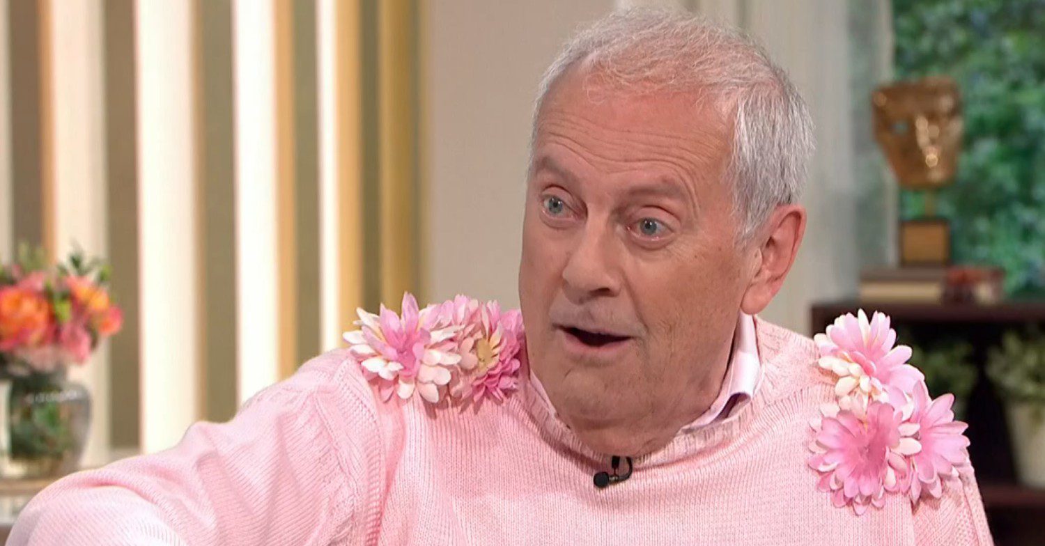Gyles Brandreth in a pink jumper talking