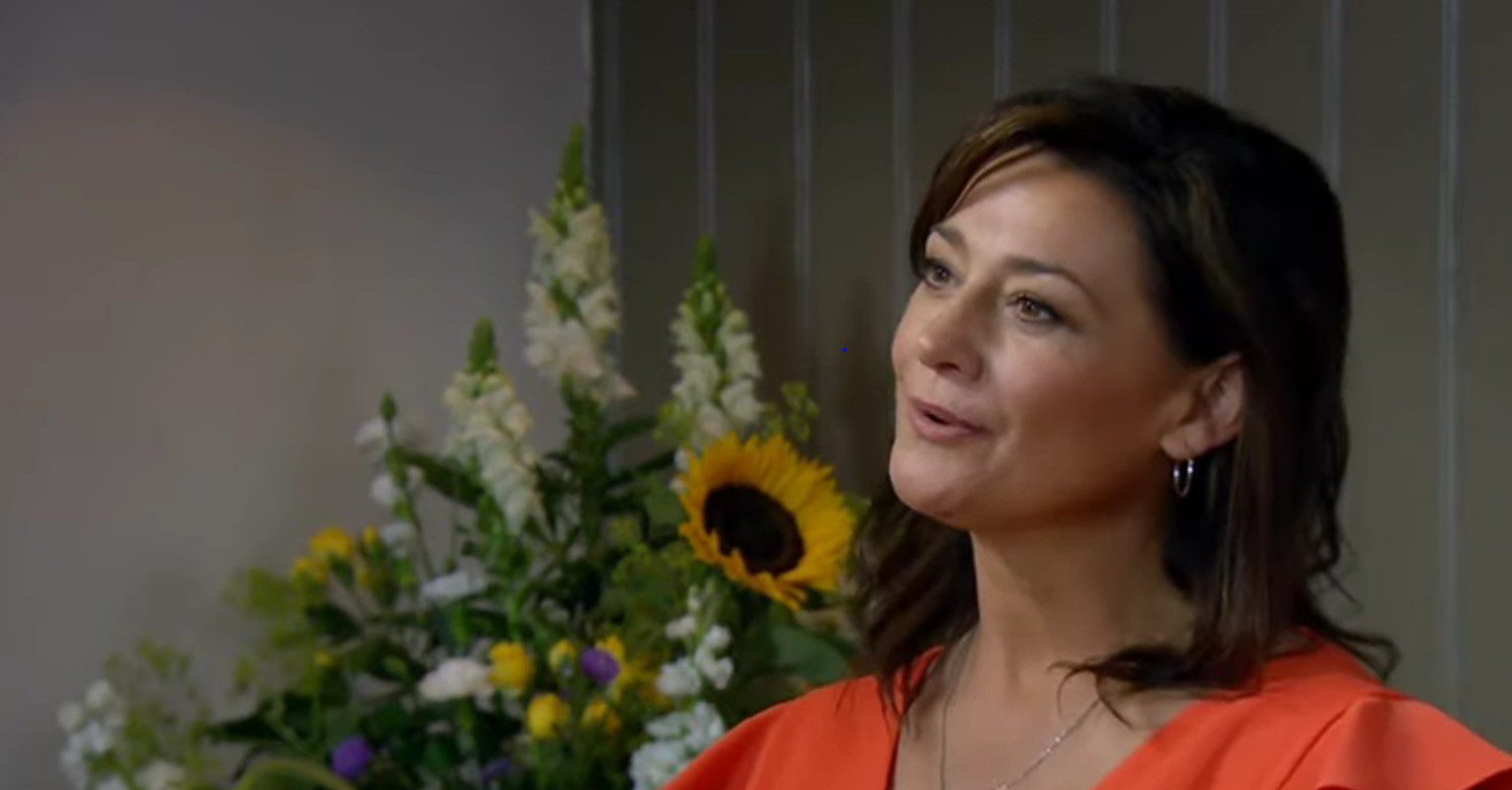 Moira smiling in a red jumpsuit on Emmerdale