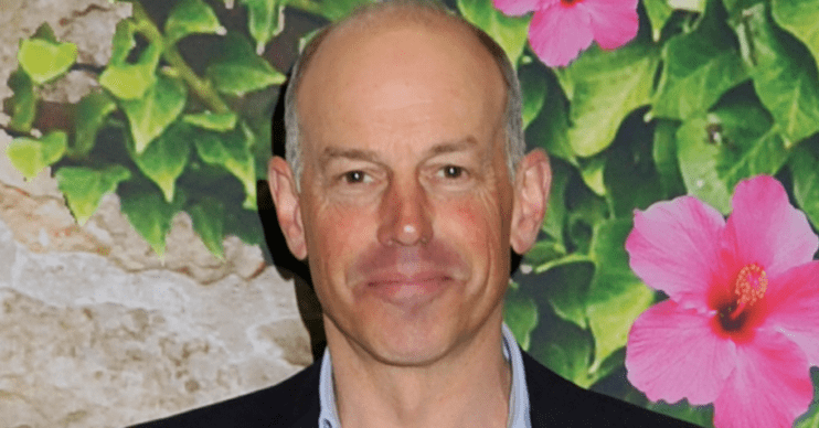 Phil Spencer straight faced against a flower wall
